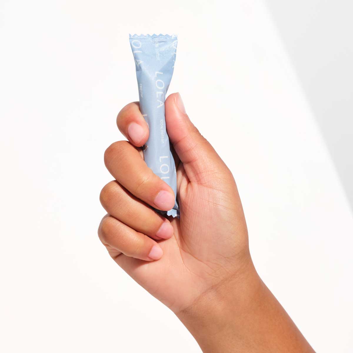 Compact plastic applicator tampons | Front view of a hand holding a regular absorbency tampon